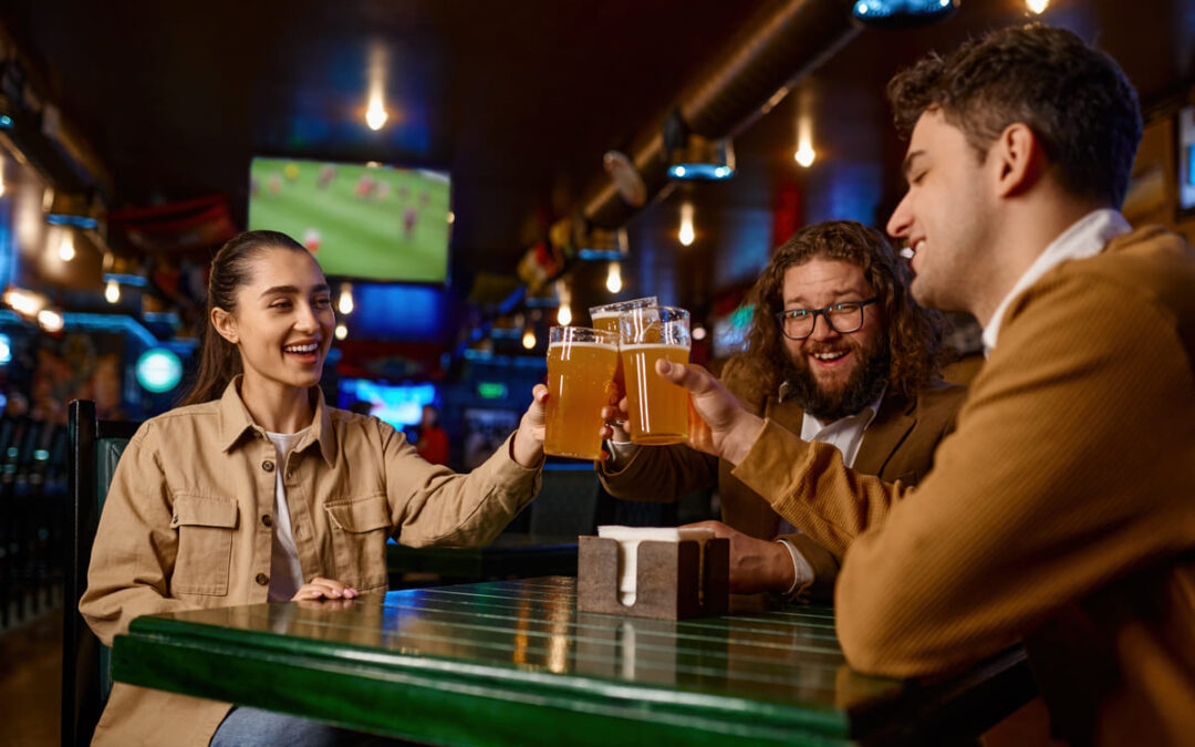 people clinking beer glasses at a bar