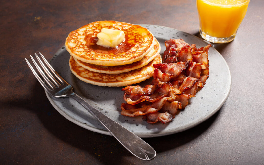 pancakes with bacon next to a glass of orange juice